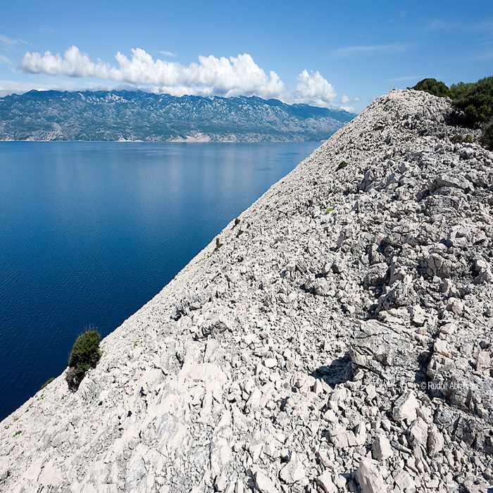 Hiking trail above the steep, rocky northeast coast of Rab, between Kamenjak and Lopar. Northern Velebit mountains in the background. Rab, Kvarner region, Croatia © Rudolf Abraham