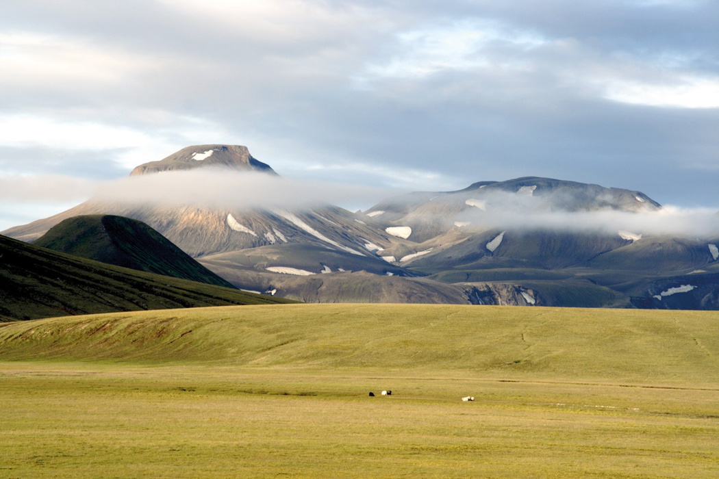 Morning mist clears from fells, seen from the gentle grasslands around Landmannahellir