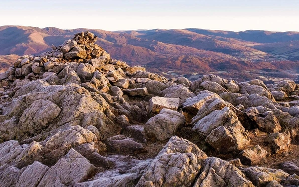 A frosty winter’s morning on the summit of Wetherlam, the Fairfield range of fells sit on the horizon